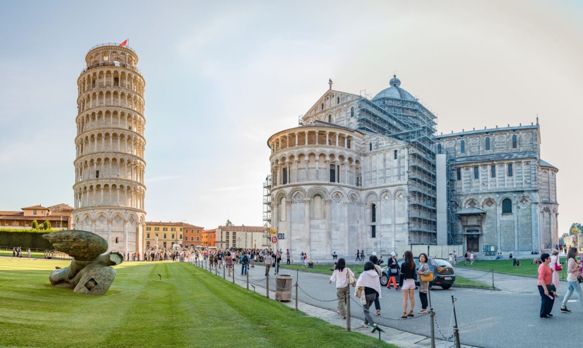 Torre inclinada de Pisa y Catedral de Pisa, Italia, con visitantes en la Piazza del Duomo bajo un cielo despejado.