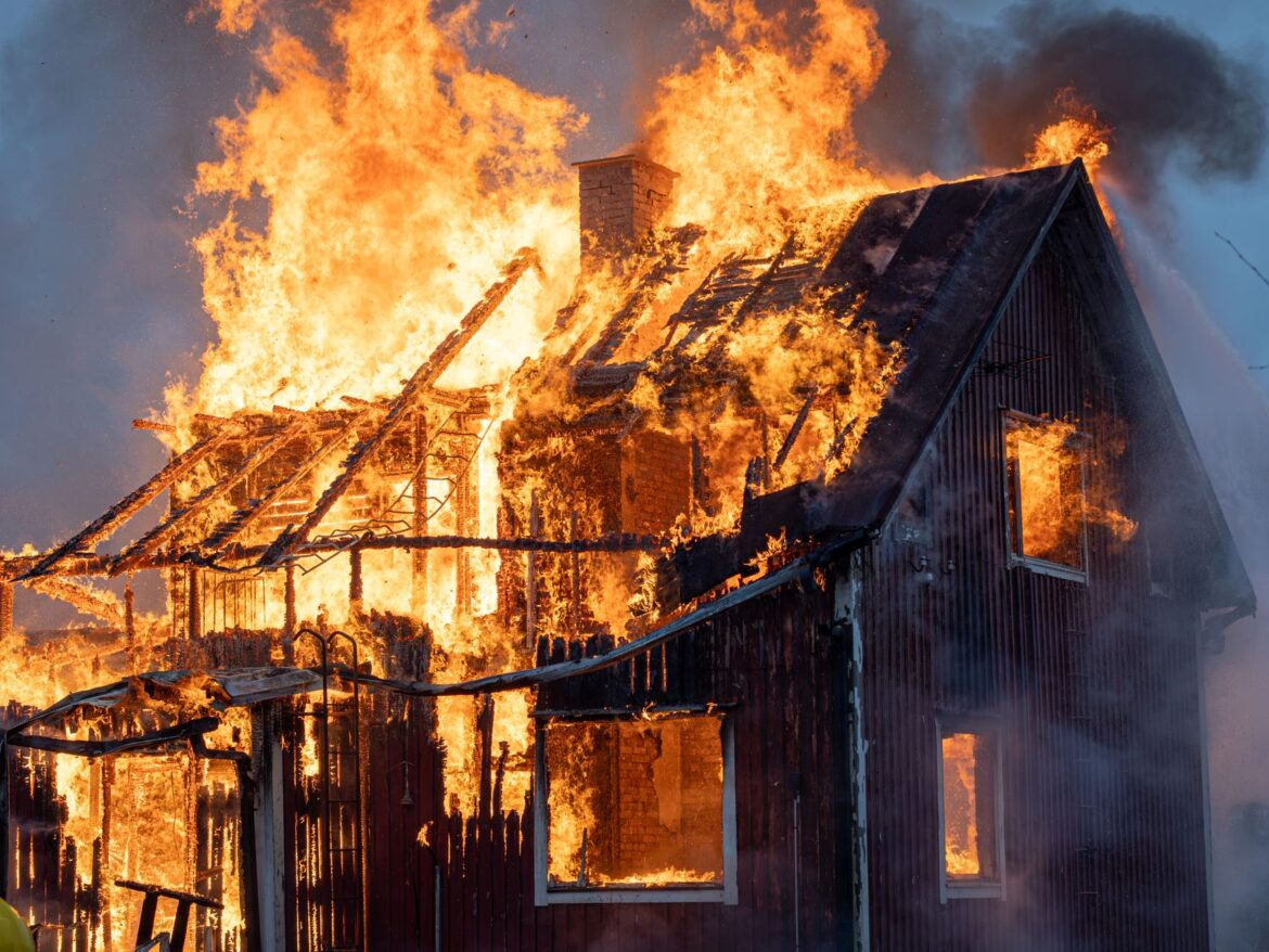 Una casa consumida por intensas llamas y humo, capturando el poder del fuego.