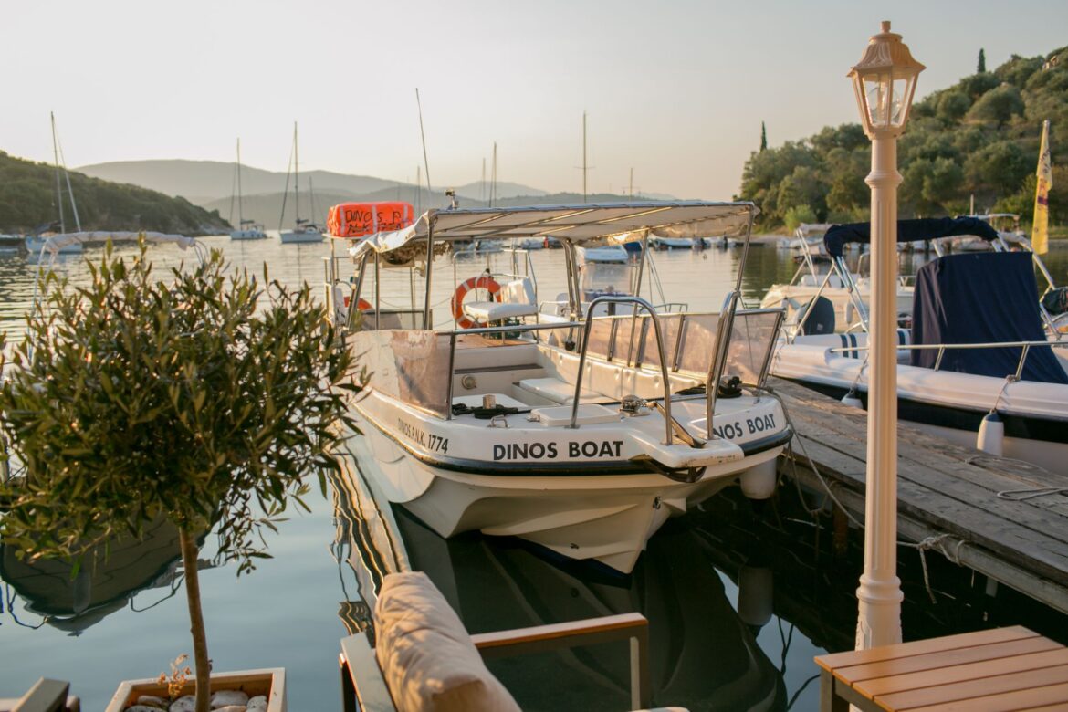 Escena tranquila de marina con barcos atracados al atardecer, rodeada de naturaleza.