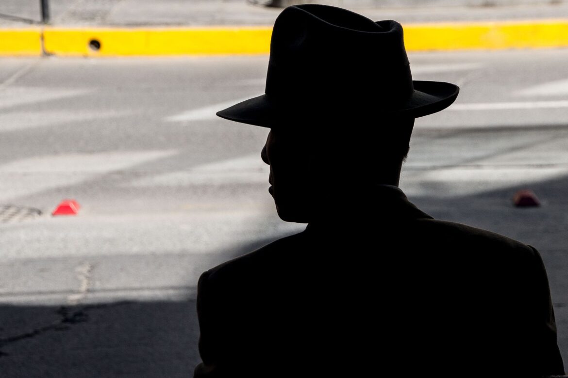 Silueta oscurecida de un hombre con sombrero, capturada en un entorno urbano.