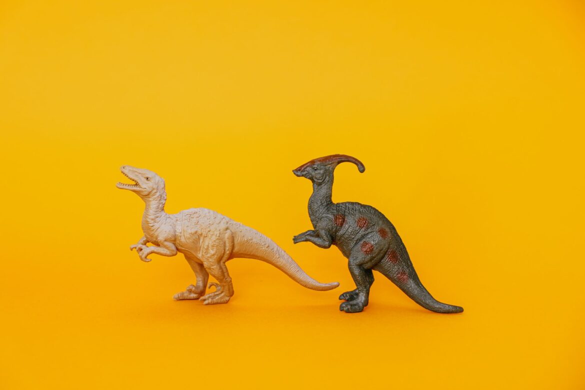 Dos figuritas de dinosaurios de juguete exhibidas sobre un fondo amarillo vibrante, fomentando la imaginación y el juego.