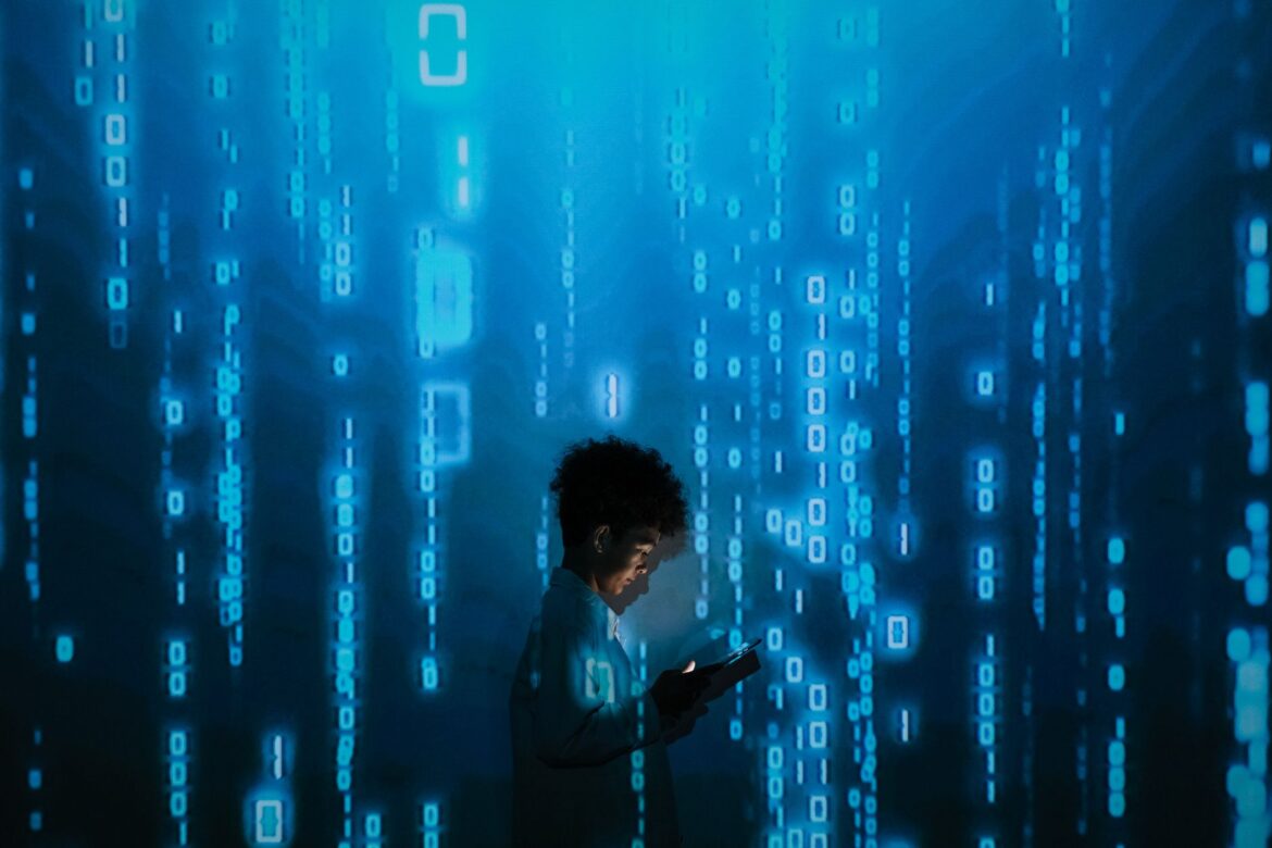 Silueta de una persona utilizando un smartphone rodeada de proyecciones de código binario digital.